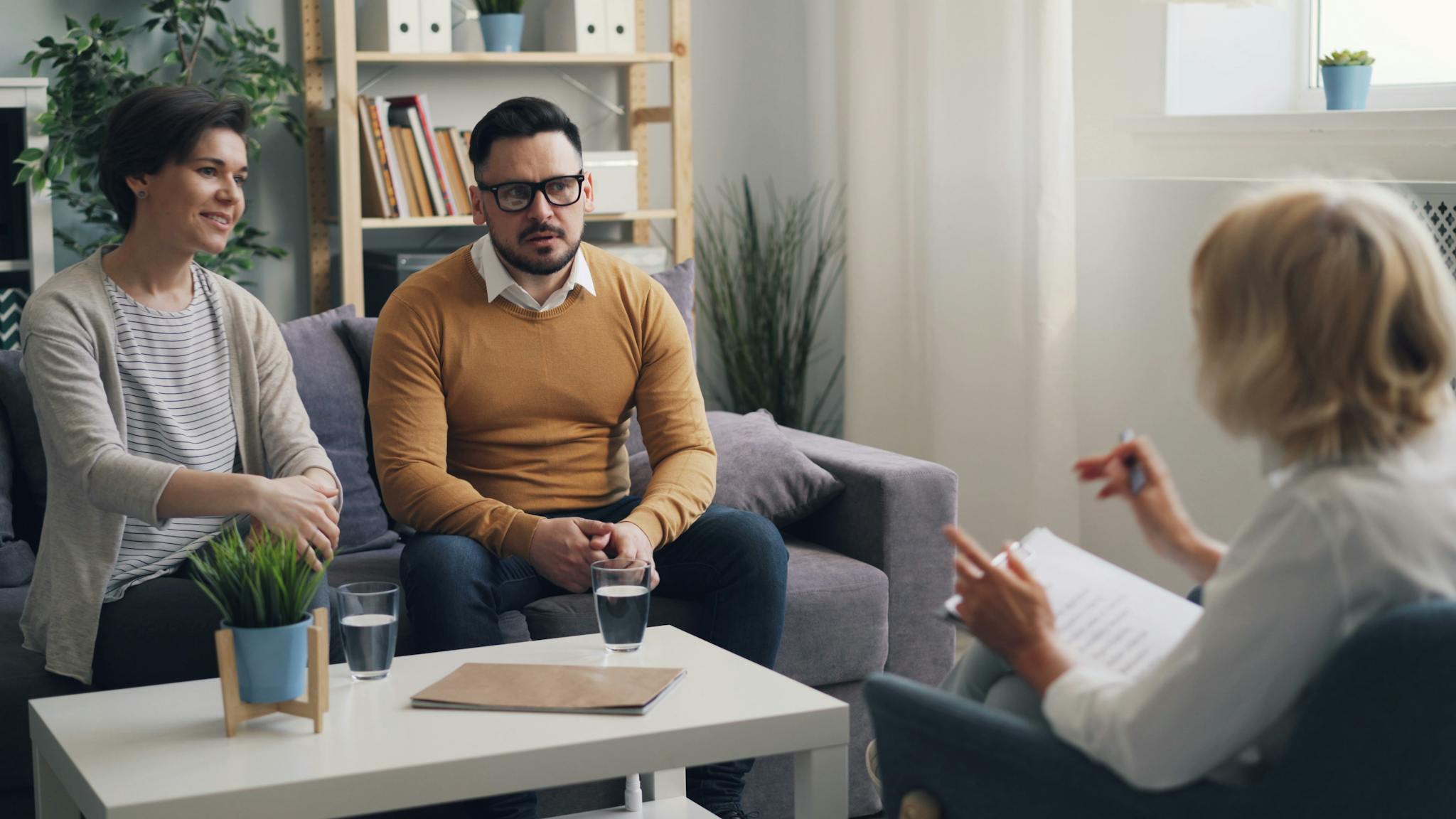 A woman and two men sitting on a couch in a living room